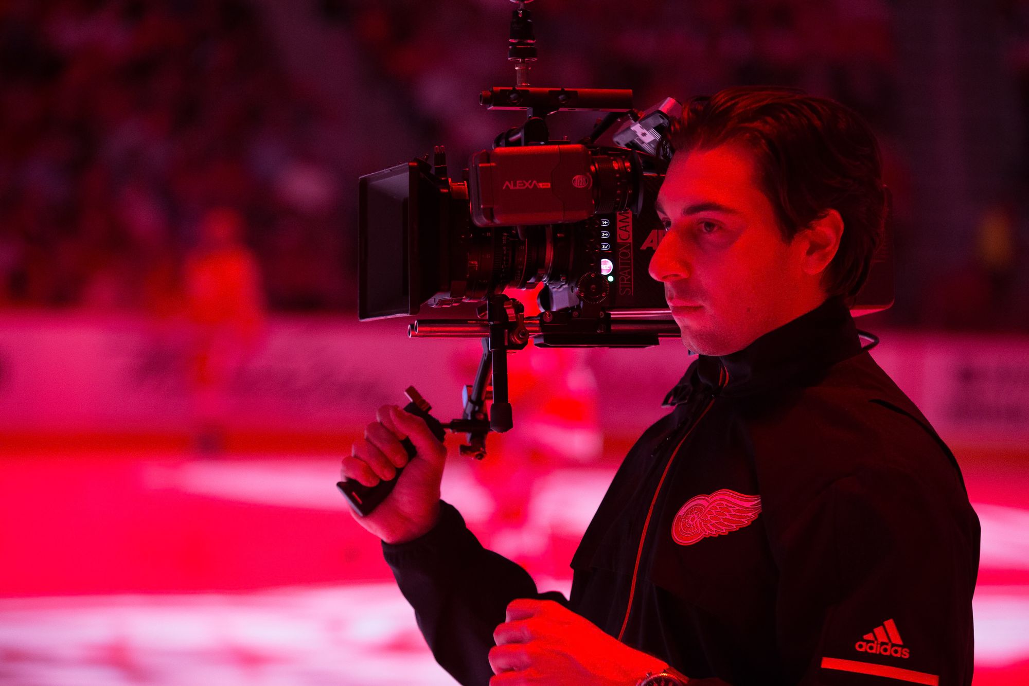 Dan Mannes operating a cinema camera on a gimbal inside the arena, lit in red