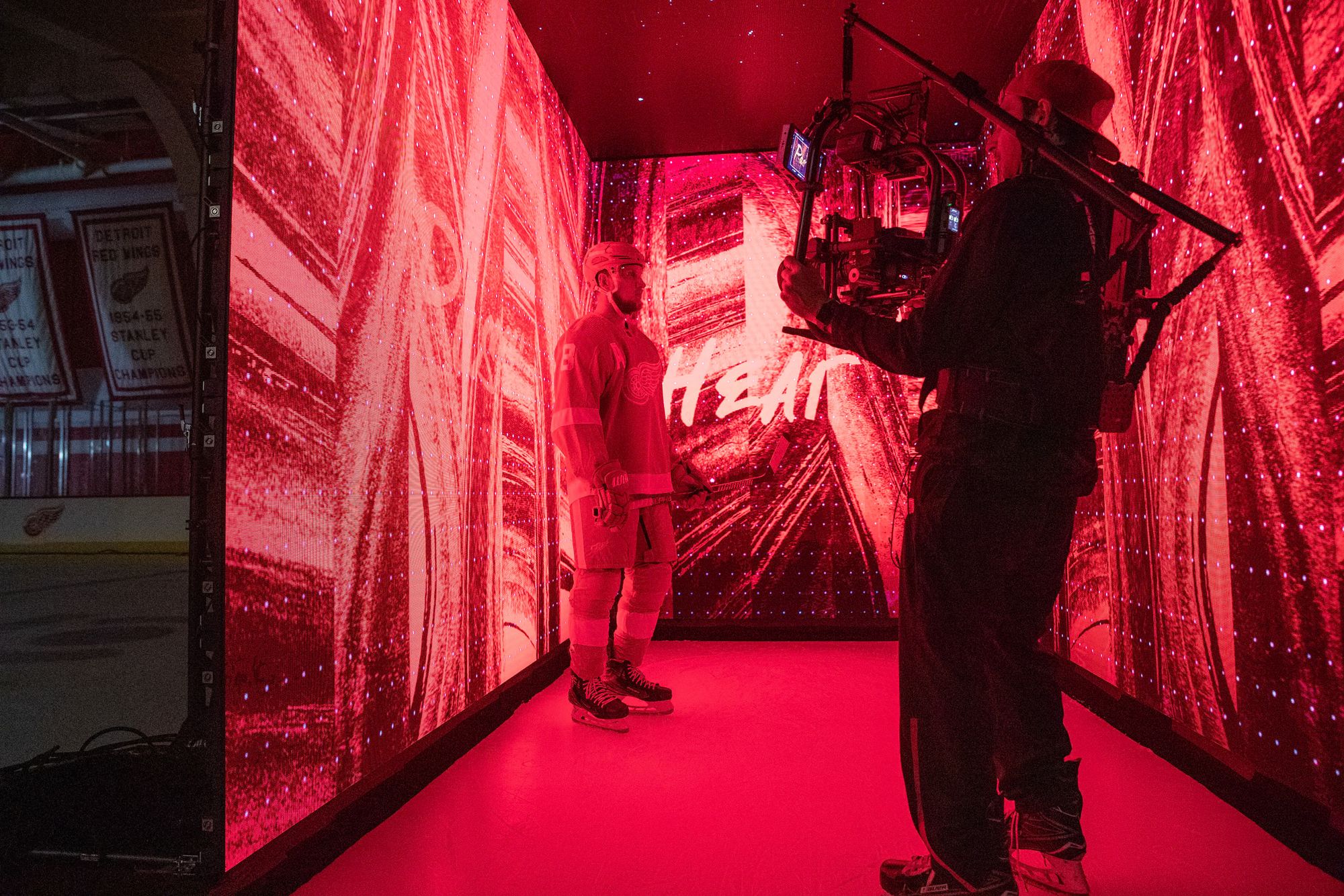 An operator with a gimbal rig filming a player walking through a red-lit LED tunnel