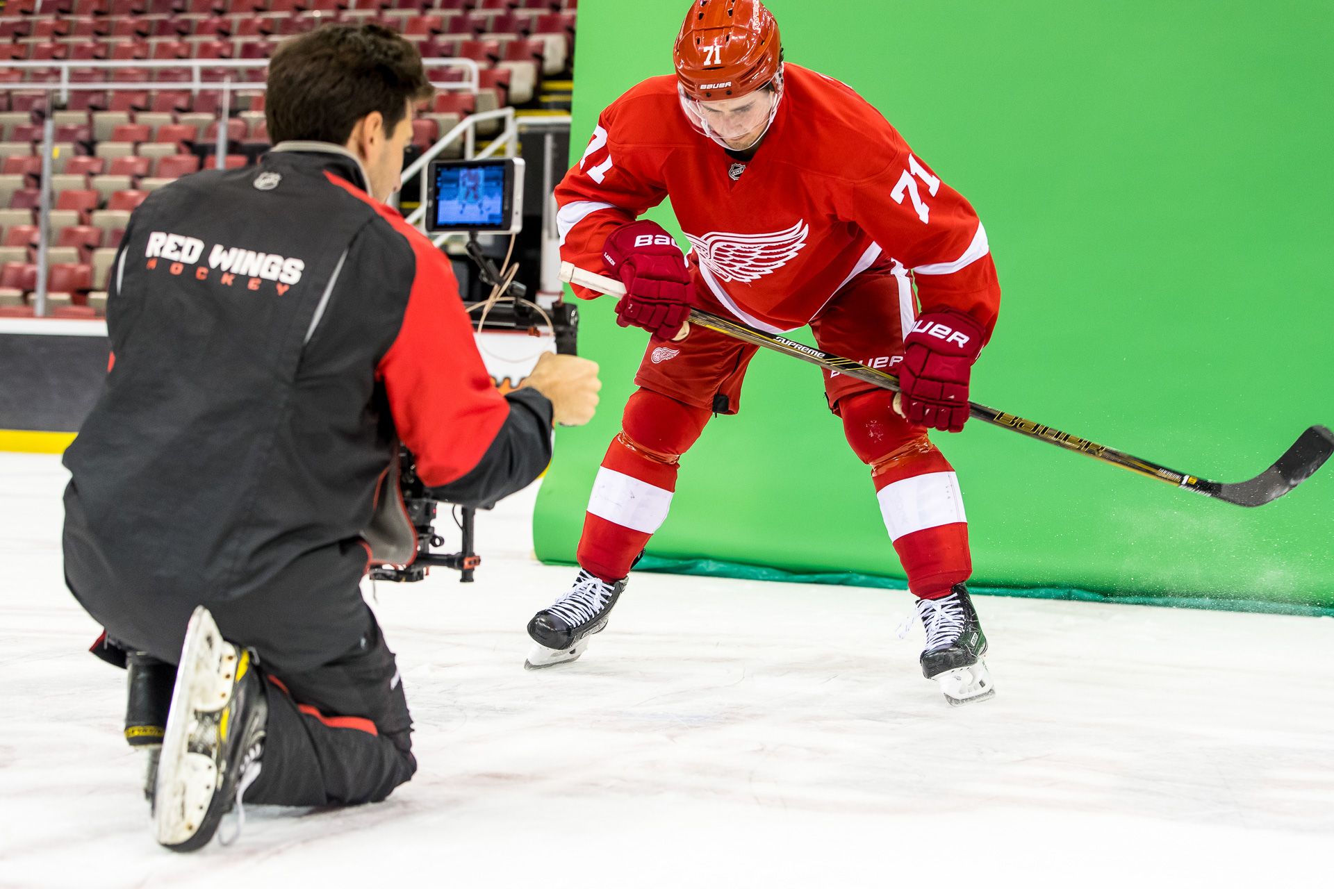 An operator on a gimbal films a Red Wings player skating against a green screen on the ice