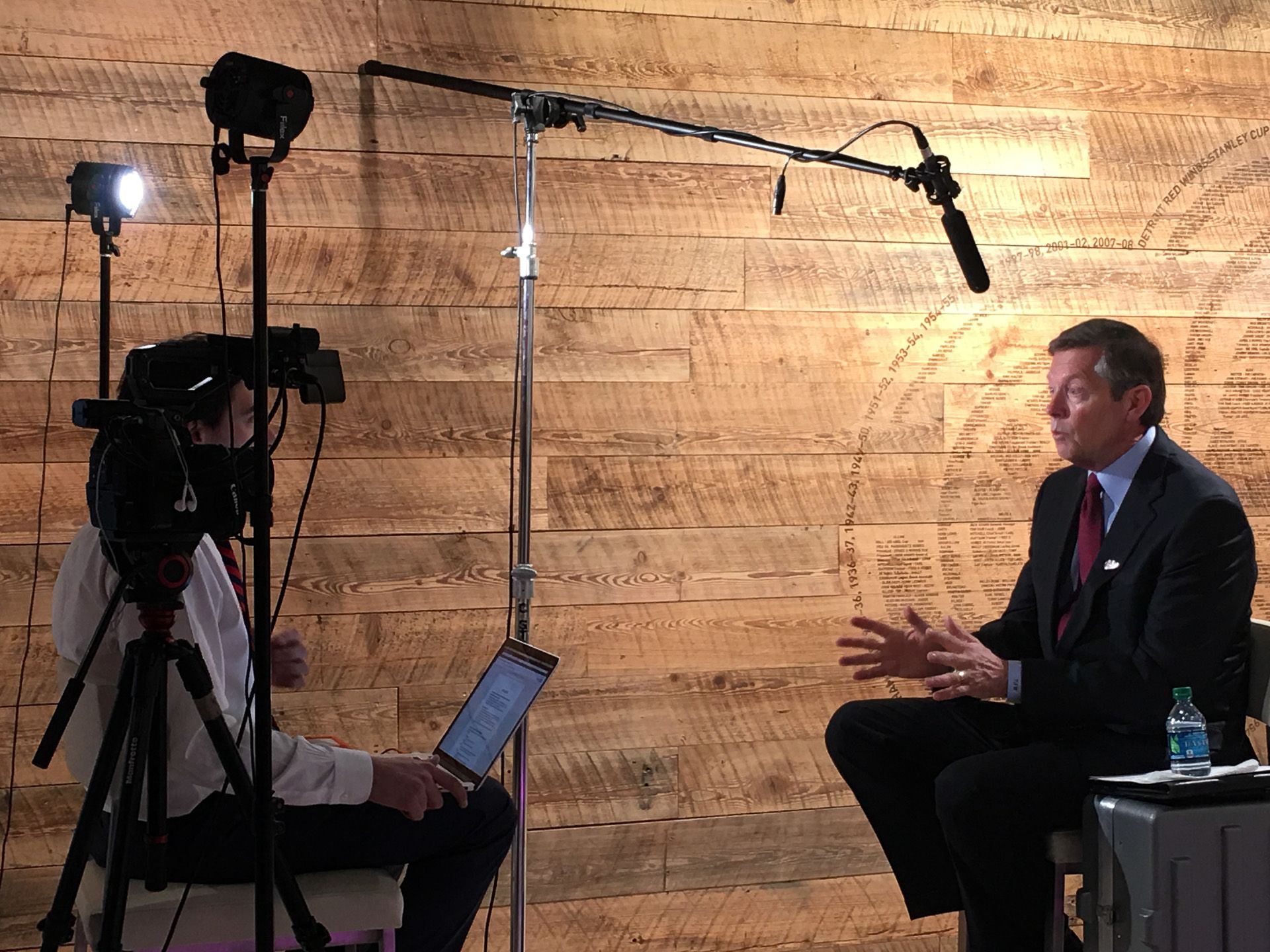 Two-camera interview setup against a wood wall with a seated subject