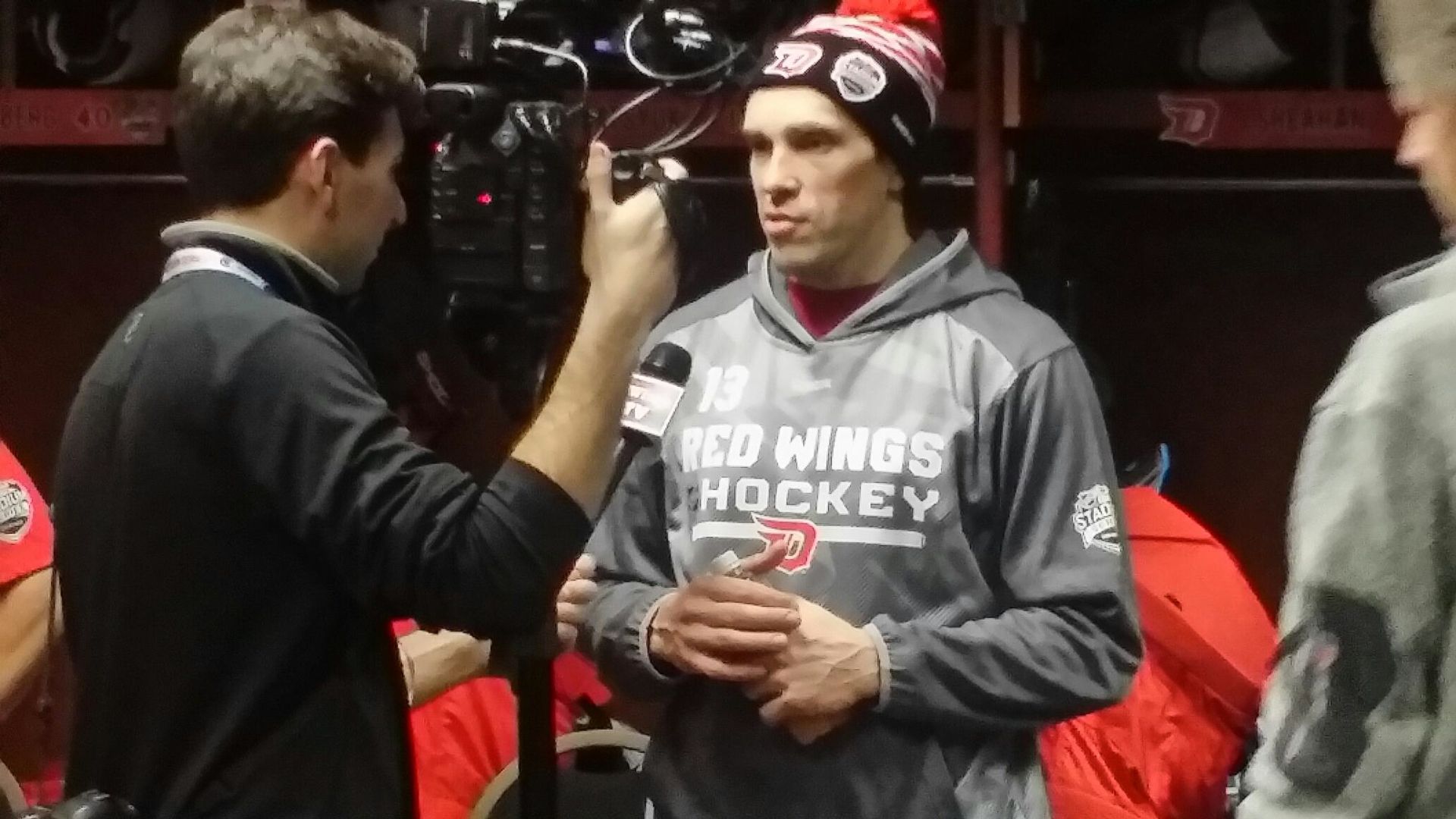 Dan filming a player interview in a crowded locker room