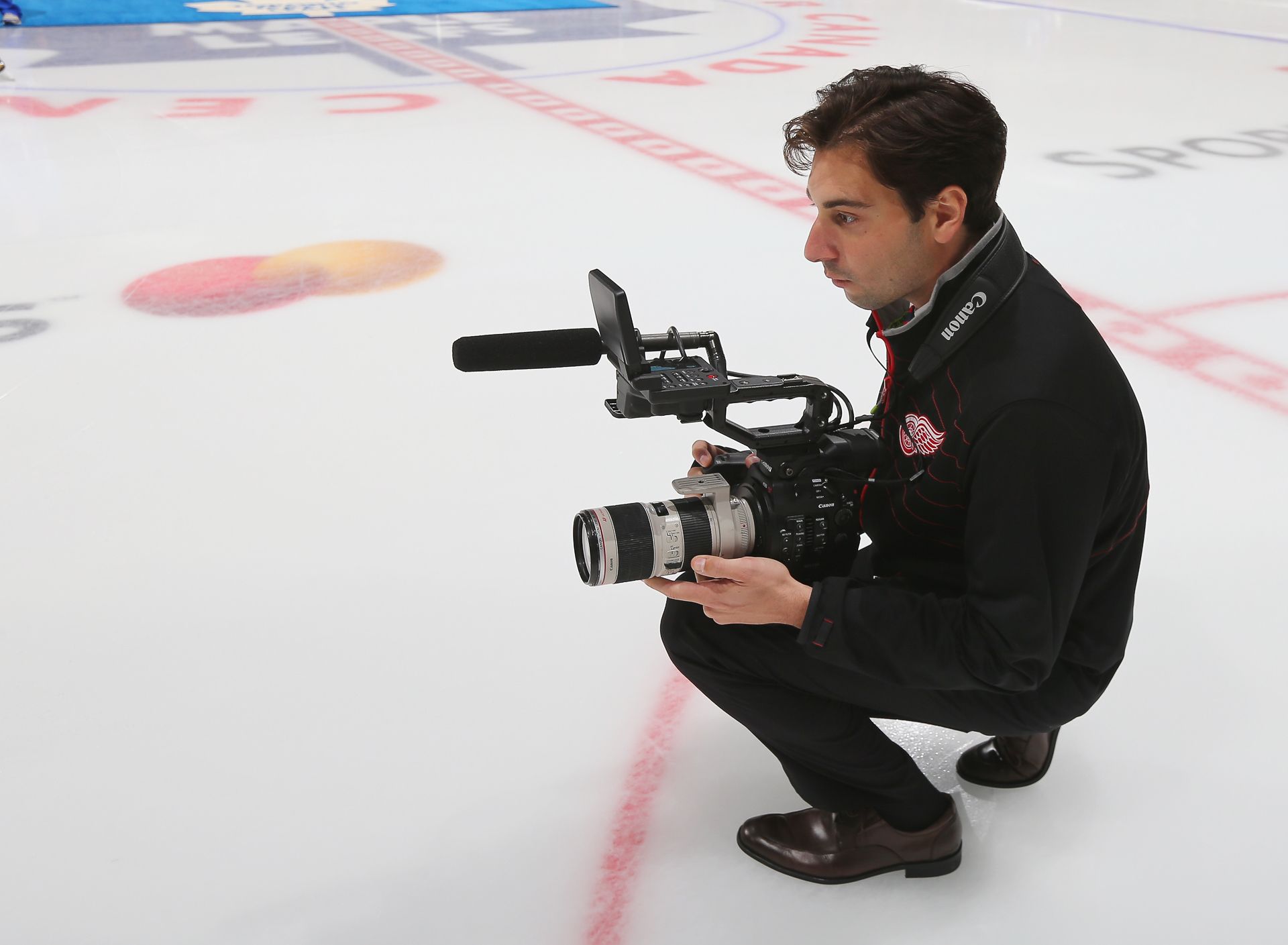 Dan crouching on the ice with a camera and shotgun mic